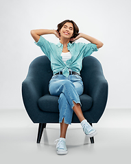 Image showing happy smiling young woman sitting in armchair