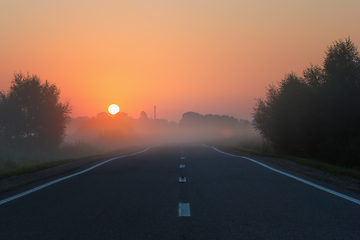 Image showing Empty Road Leading to Golden Sunrise on Foggy Morning