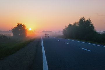 Image showing Car Drives On The Suburban Road On A Foggy Morning During Sunrise