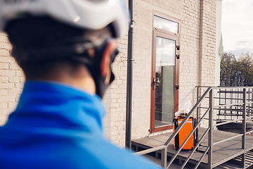 Image showing Contacless delivery service during quarantine. Man delivers food and shopping bags during isolation