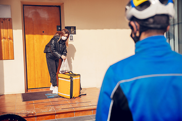 Image showing Contacless delivery service during quarantine. Man delivers food and shopping bags during isolation