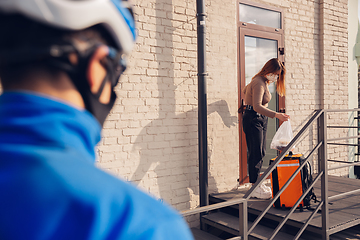 Image showing Contacless delivery service during quarantine. Man delivers food and shopping bags during isolation