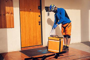 Image showing Contacless delivery service during quarantine. Man delivers food and shopping bags during isolation