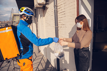 Image showing Contacless delivery service during quarantine. Man delivers food and shopping bags during isolation