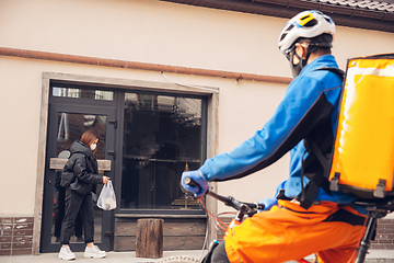 Image showing Contacless delivery service during quarantine. Man delivers food and shopping bags during isolation