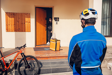 Image showing Contacless delivery service during quarantine. Man delivers food and shopping bags during isolation