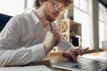 Image showing Caucasian young man in business attire working in office, job, online studying