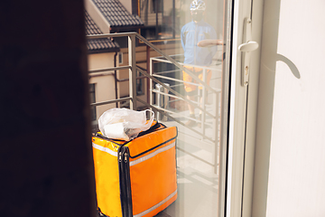 Image showing Contacless delivery service during quarantine. Man delivers food and shopping bags during isolation