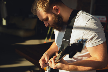 Image showing Caucasian musician playing guitar during online concert at home isolated and quarantined, impressive improvising