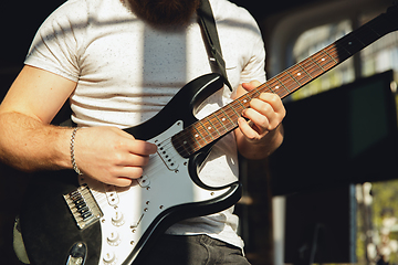 Image showing Caucasian musician playing guitar during online concert at home isolated and quarantined, impressive improvising, close up