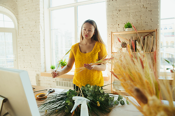 Image showing Florist at work: woman shows how to make bouquet, working at home concept, choosing plants for composition