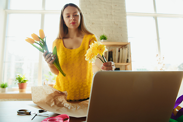 Image showing Florist at work: woman shows how to make bouquet with tulips, working at home concept, choosing flowers