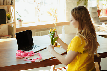 Image showing Florist at work: woman shows how to make bouquet with tulips, working at home concept, decoration