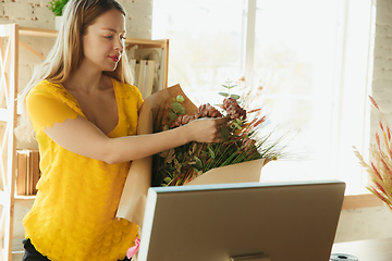 Image showing Florist at work: woman shows how to make bouquet, working at home concept, demonstrating the result