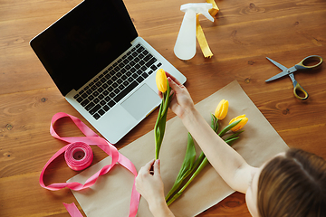 Image showing Florist at work: woman shows how to make bouquet with tulips, working at home concept, top view