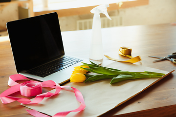 Image showing Florist at work: table with tulips and daffodils, ribbons and coverage paper against laptop, prepared for workshop