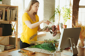 Image showing Florist at work: woman shows how to make bouquet, working at home concept, choosing plants for composition