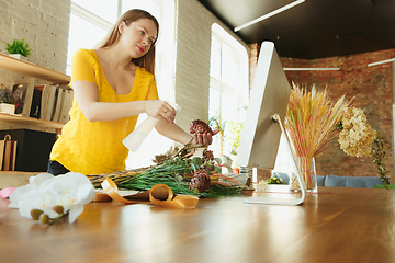 Image showing Florist at work: woman shows how to make bouquet, working at home concept, spraying