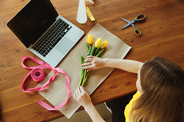 Image showing Florist at work: woman shows how to make bouquet with tulips, working at home concept, top view