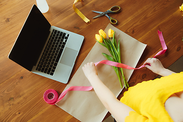 Image showing Florist at work: woman shows how to make bouquet with tulips, working at home concept, top view