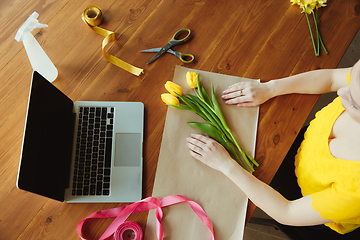 Image showing Florist at work: woman shows how to make bouquet with tulips, working at home concept, top view