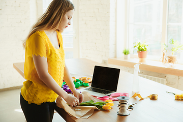 Image showing Florist at work: woman shows how to make bouquet with tulips, working at home concept, preparing flowers