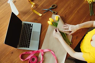 Image showing Florist at work: woman shows how to make bouquet with tulips, working at home concept, top view