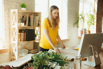 Image showing Florist at work: woman shows how to make bouquet, working at home concept, choosing plants for composition