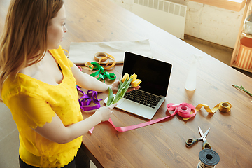 Image showing Florist at work: woman shows how to make bouquet with tulips, working at home concept, preparing flowers