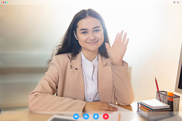 Image showing Young woman talking, working in videoconference with co-workers at office or living room. Online business, education during quarantine.