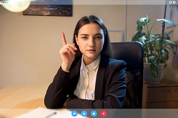 Image showing Young woman talking, working in videoconference with co-workers at office or living room. Online business, education during quarantine.