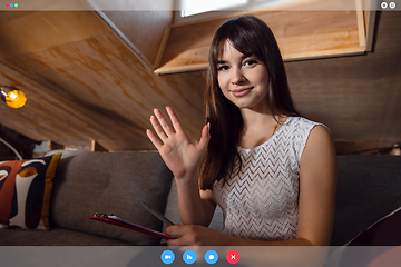 Image showing Young woman talking, working in videoconference with co-workers at office or living room. Online business, education during quarantine.