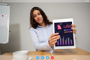 Image showing Young woman talking, working in videoconference with co-workers at office or living room. Online business, education during quarantine.