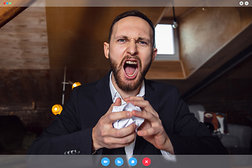 Image showing Young man talking, working in videoconference with co-workers at office or living room. Online business, education during quarantine.