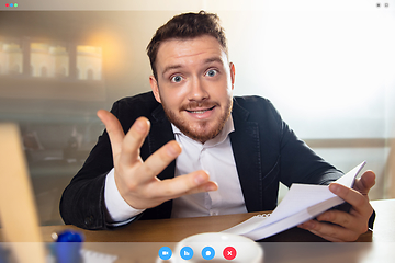 Image showing Young man talking, working in videoconference with co-workers at office or living room. Online business, education during quarantine.