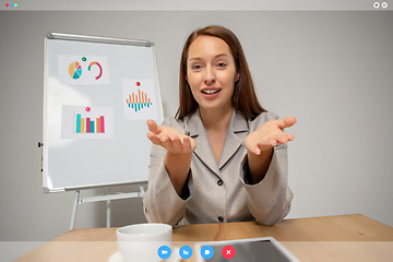 Image showing Young woman talking, working in videoconference with co-workers at office or living room. Online business, education during quarantine.