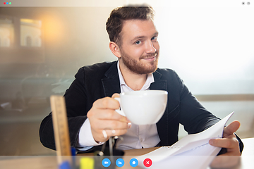 Image showing Young man talking, working in videoconference with co-workers at office or living room. Online business, education during quarantine.