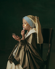 Image showing Medieval little girl as a lady with a pearl earring on dark studio background. Concept of comparison of eras, childhood. Stylish creative design, art vision, new look of artwork.