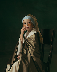 Image showing Medieval little girl as a lady with a pearl earring on dark studio background. Concept of comparison of eras, childhood. Stylish creative design, art vision, new look of artwork.