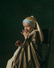 Image showing Medieval little girl as a lady with a pearl earring on dark studio background. Concept of comparison of eras, childhood. Stylish creative design, art vision, new look of artwork.