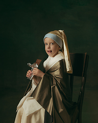 Image showing Medieval little girl as a lady with a pearl earring on dark studio background. Concept of comparison of eras, childhood. Stylish creative design, art vision, new look of artwork.