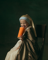 Image showing Medieval little girl as a lady with a pearl earring on dark studio background. Concept of comparison of eras, childhood. Stylish creative design, art vision, new look of artwork.