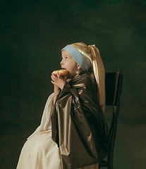 Image showing Medieval little girl as a lady with a pearl earring on dark studio background. Concept of comparison of eras, childhood. Stylish creative design, art vision, new look of artwork.