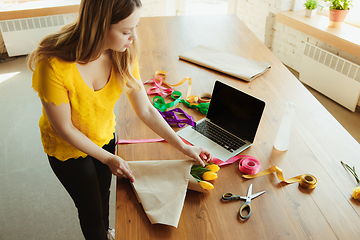 Image showing Florist at work: woman shows how to make bouquet with tulips, working at home concept, using coverage paper