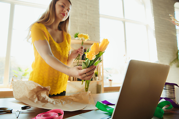 Image showing Florist at work: woman shows how to make bouquet with tulips, working at home concept, choosing flowers