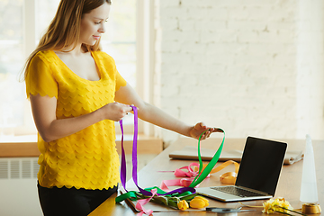 Image showing Florist at work: woman shows how to make bouquet with tulips, working at home concept, using ribbons