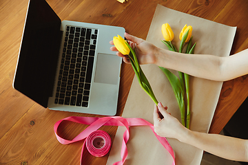 Image showing Florist at work: woman shows how to make bouquet with tulips, working at home concept, top view