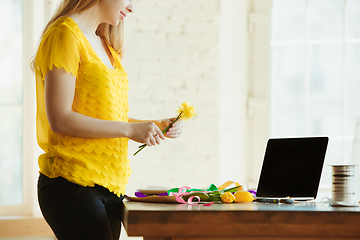 Image showing Florist at work: woman shows how to make bouquet with tulips, working at home concept, adds daffodils