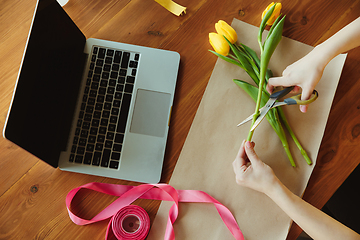 Image showing Florist at work: woman shows how to make bouquet with tulips, working at home concept, top view