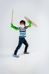 Image showing Little caucasian boy as a warrior in fight with coronavirus pandemic, with a shield, a sword and a toilet paper bandoleer, attacking